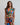Woman wearing a colorful patterned set against a plain background